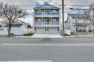 a white house with two garage doors on a street at Spacious Wildwood Condo Walk to Beach! in Wildwood