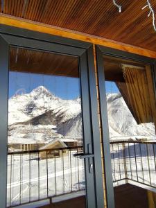 een open deur met uitzicht op een met sneeuw bedekte berg bij Cottage Paradise in Kazbegi