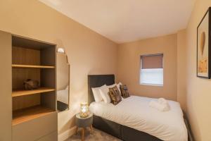 een kleine slaapkamer met een bed en een boekenplank bij Modern 2 Bed Ground Floor - Private Parking in Windsor