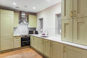 een keuken met groene kasten en een wastafel bij Modern 2 Bed Ground Floor - Private Parking in Windsor