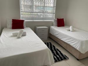2 camas en una habitación con almohadas blancas y rojas en DURBAN BEACH HOLIDAY HOME, en Durban