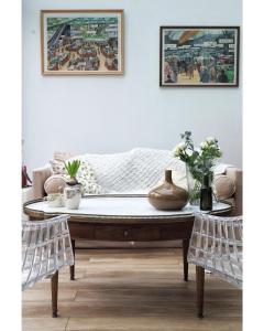 LA MAISON d'HORTENSE, maison de charme et de caractère في تولوز: طاولة قهوة في غرفة معيشة مع لوحات على الحائط