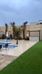 a patio with two chairs and a table and a lawn at sea breeze RAK in Ras al Khaimah