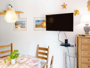a dining room table with a flat screen tv on a wall at Villa Gruissan, 3 pièces, 4 personnes - FR-1-409-31 in Gruissan