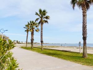 a sidewalk next to a beach with palm trees at Villa Gruissan, 3 pièces, 4 personnes - FR-1-409-31 in Gruissan