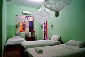 two beds in a room with green walls at KFG Guesthouse in Thakhek