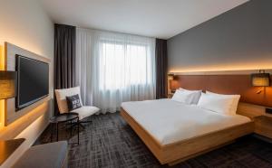 a hotel room with a large bed and a tv at Precise House Düsseldorf Airport in Ratingen