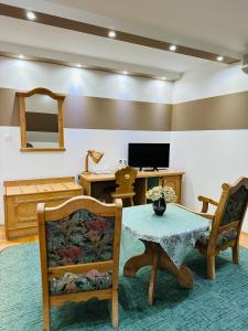 sala de estar con mesa, sillas y TV en Öreg Prés Butikhotel en Mór