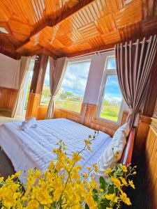 a bedroom with a bed and two windows at KHÁNH AN HOTEL in Da Lat