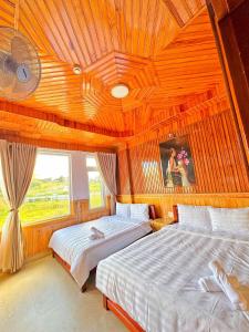 two beds in a room with a wooden ceiling at KHÁNH AN HOTEL in Da Lat