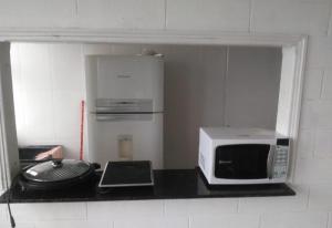 una cocina con microondas y un ordenador portátil en una encimera en Apartamento na Praia do Morro, en Guarapari