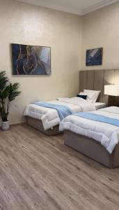 two beds in a room with wood floors at sea breeze RAK in Ras al Khaimah