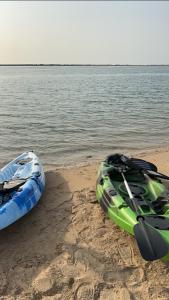 two kayaks sitting on a beach next to the water at sea breeze RAK in Ras al Khaimah