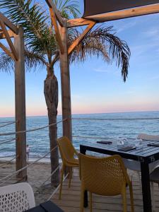 una mesa y sillas en la playa con el océano en Mas Rose des Vents, en Le Barcarès