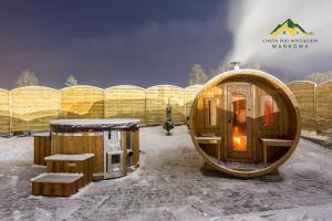 una casa hobbit de madera con un banco en la nieve en Chata pod wyciągiem, en Wańkowa