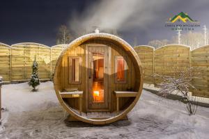 eine runde Holzhütte im Schnee mit einem Zaun in der Unterkunft Chata pod wyciągiem in Wańkowa