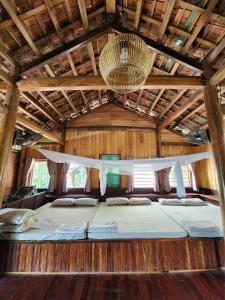 Una cama en medio de una habitación de madera en TINA LAKESIDE AO ĐÔI Homestay Phước Hải, en Hội Mỹ