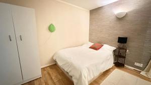ein kleines Schlafzimmer mit einem weißen Bett und einem roten Kissen in der Unterkunft Top floor studio apartment in Enfield Lock