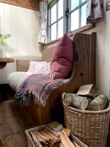 Rushford Shepherd's Hut في نيوتن أبوت: غرفة بها أريكة وسلة مع الوسائد
