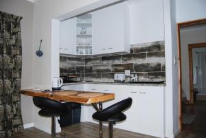 a kitchen with a wooden table and black stools at Urban Bush Lodge in Howick