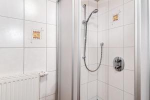 a shower in a bathroom with white tiles at Prinzbachhof in Mühlenbach