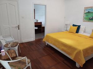 a bedroom with a yellow bed and a chair at Explora Prestige in Blue Bay