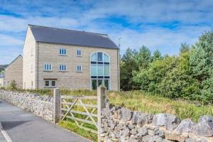 a brick building with a stone wall and a fence at Otterhole Barn Holiday Apartment in Buxton