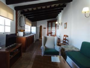 een woonkamer met een bank en een keuken bij Hacienda los Majadales in Conil de la Frontera