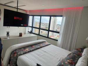 a bedroom with a bed and a large window at Flat próximo ao Shopping Campo Grande in Campo Grande