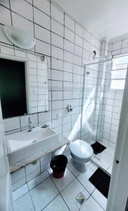 a white bathroom with a sink and a toilet at Guarujá Praia Hotel Econômico in Guarujá