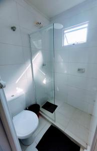 a bathroom with a toilet and a glass shower at Guarujá Praia Hotel Econômico in Guarujá