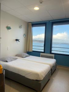 a bedroom with two beds and two large windows at CLLCM - Club Leo Lagrange de Camaret-sur-Mer in Camaret-sur-Mer