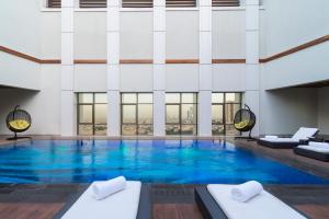 een groot zwembad met blauw water in een gebouw bij Movenpick Hotel and Residences Riyadh in Riyad