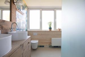 a bathroom with a sink and a toilet and windows at Vegan B&B De Groene Mus in Wervershoof