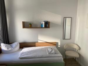 a bedroom with a bed with a chair and a mirror at Circus Hostal Putbus in Putbus