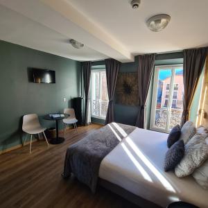 a bedroom with a large bed and some windows at Le Grand Hotel in Barcelonnette