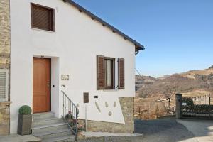 uma casa branca com uma porta castanha e escadas em Ca ed Giuanoto em Santo Stefano Belbo
