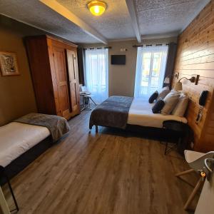 um quarto com 2 camas e piso em madeira em Le Grand Hotel em Barcelonnette