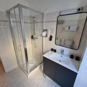 a bathroom with a shower and a sink and a mirror at Le Grand Hotel in Barcelonnette