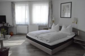 1 dormitorio con 1 cama grande con sábanas y almohadas blancas en Boardinghaus zu Coburg, en Coburg