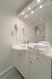 a white bathroom with a sink and a mirror at Hotel Panorama in Bouillon