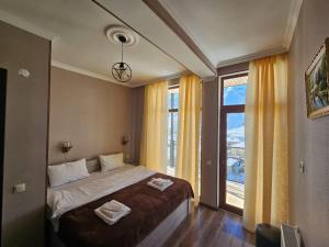 a bedroom with a bed and a large window at DISCOVER KAZBEGi HOTEL in Kazbegi