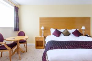 ドーチェスターにあるGeorge Albert Hotel & Spaのベッドとテーブルが備わるホテルルームです。