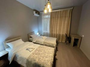 a hotel room with three beds and a window at Hotel Lumi in Zugdidi