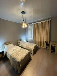 a bedroom with two beds and a table and a chandelier at Hotel Lumi in Zugdidi