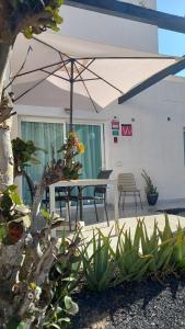 une terrasse avec une table et un parasol dans l'établissement Corralejo Suite Pool & Gardens - Alisios Playa, à Corralejo