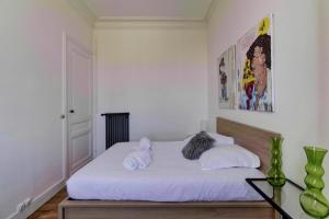 um quarto com uma cama com lençóis brancos e almofadas em LE VICTOR - Grand et lumineux T3 em Bordeaux