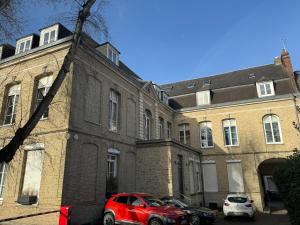 een rode auto geparkeerd voor een bakstenen gebouw bij Studio centre ville le saint'oh in Saint-Omer