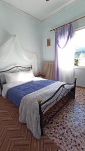 a bedroom with a bed with a blue comforter and a window at O'GERA Greek resort house in the mountains in Kókla