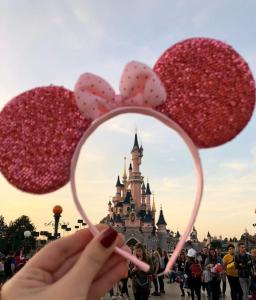 una persona sosteniendo dos corazones y un espejo frente a un castillo en Disney et Paris pour 4 personnes RER A, en Champs-Sur-Marne